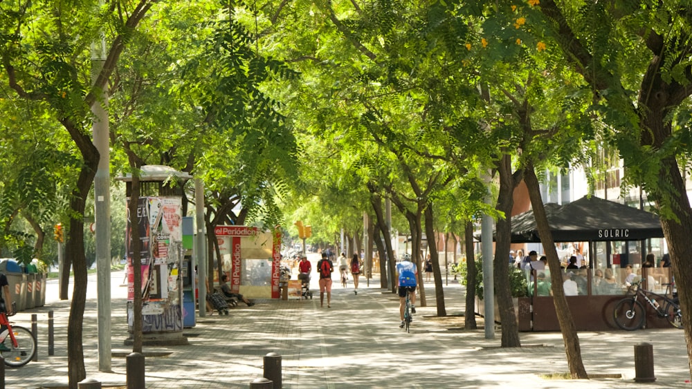 a group of people walking on a sidewalk with Cours Mirabeau in the background