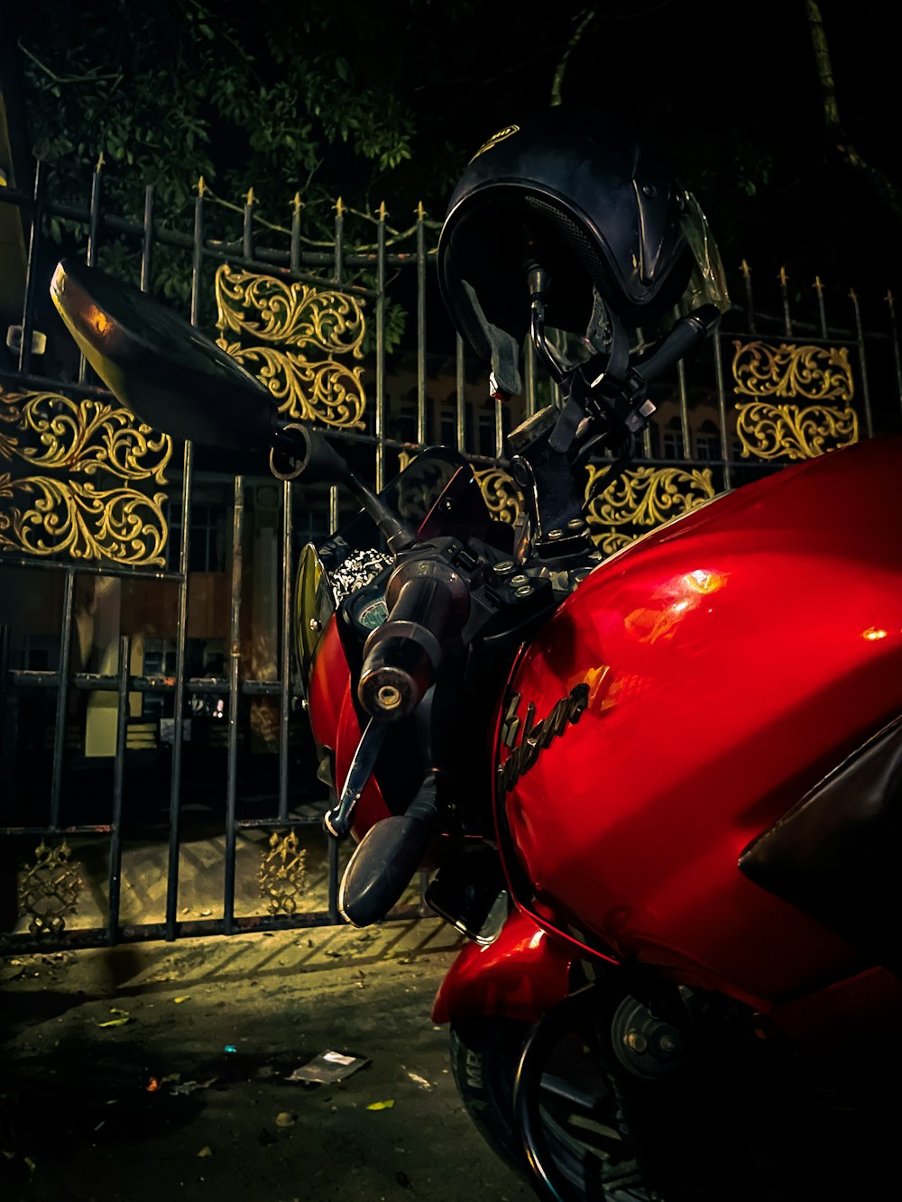 a red motorcycle parked in front of a gate
