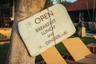 The restaurant’s wooden sign hanging by the roadside, framed by tall grasses and the open countryside.