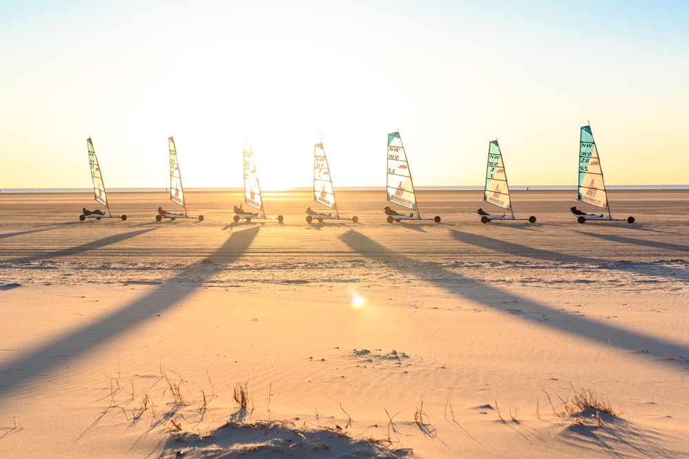 a group of sailboats on a sandy beach