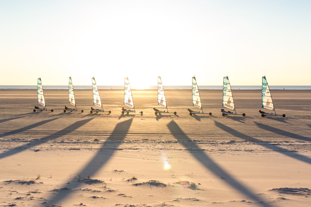 a group of sailboats on a sandy beach