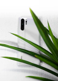A sleek smartphone resting on a smooth white surface with soft green gradients in the background.