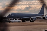 Modern fuel tanker surrounded by a large fleet of vehicles under a cloudy airport sky.