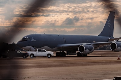 Modern fuel tanker surrounded by a large fleet of vehicles under a cloudy airport sky.