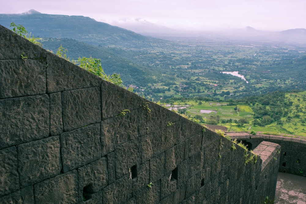 a stone wall with a city in the background