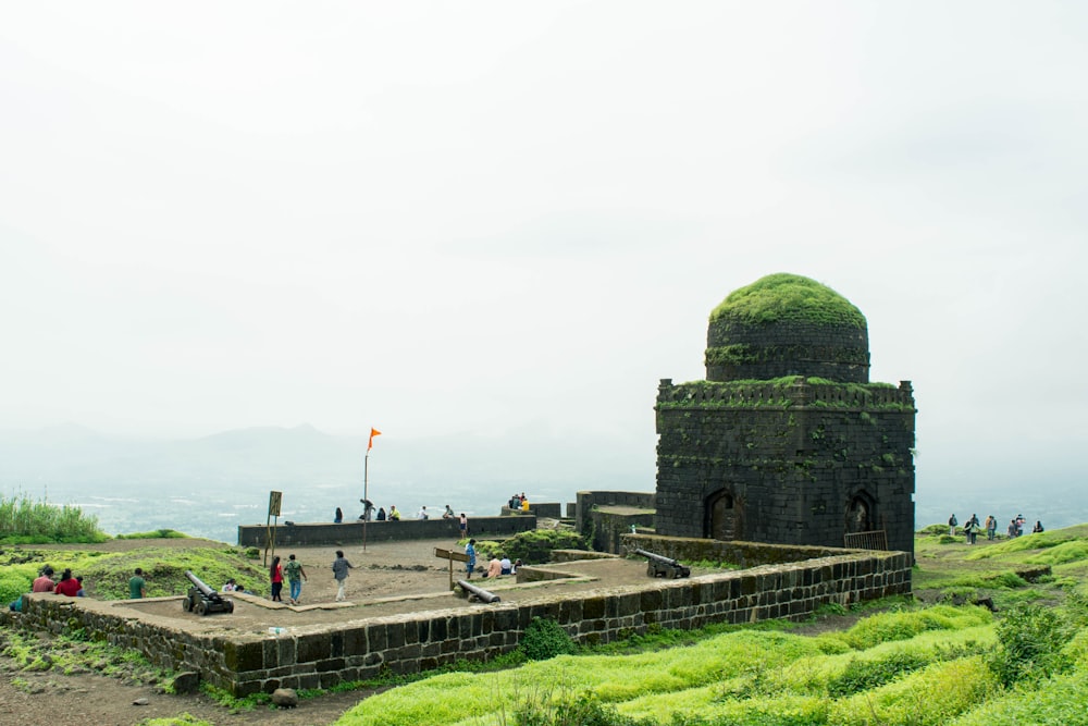 a stone building with a dome on top and a group of people walking around