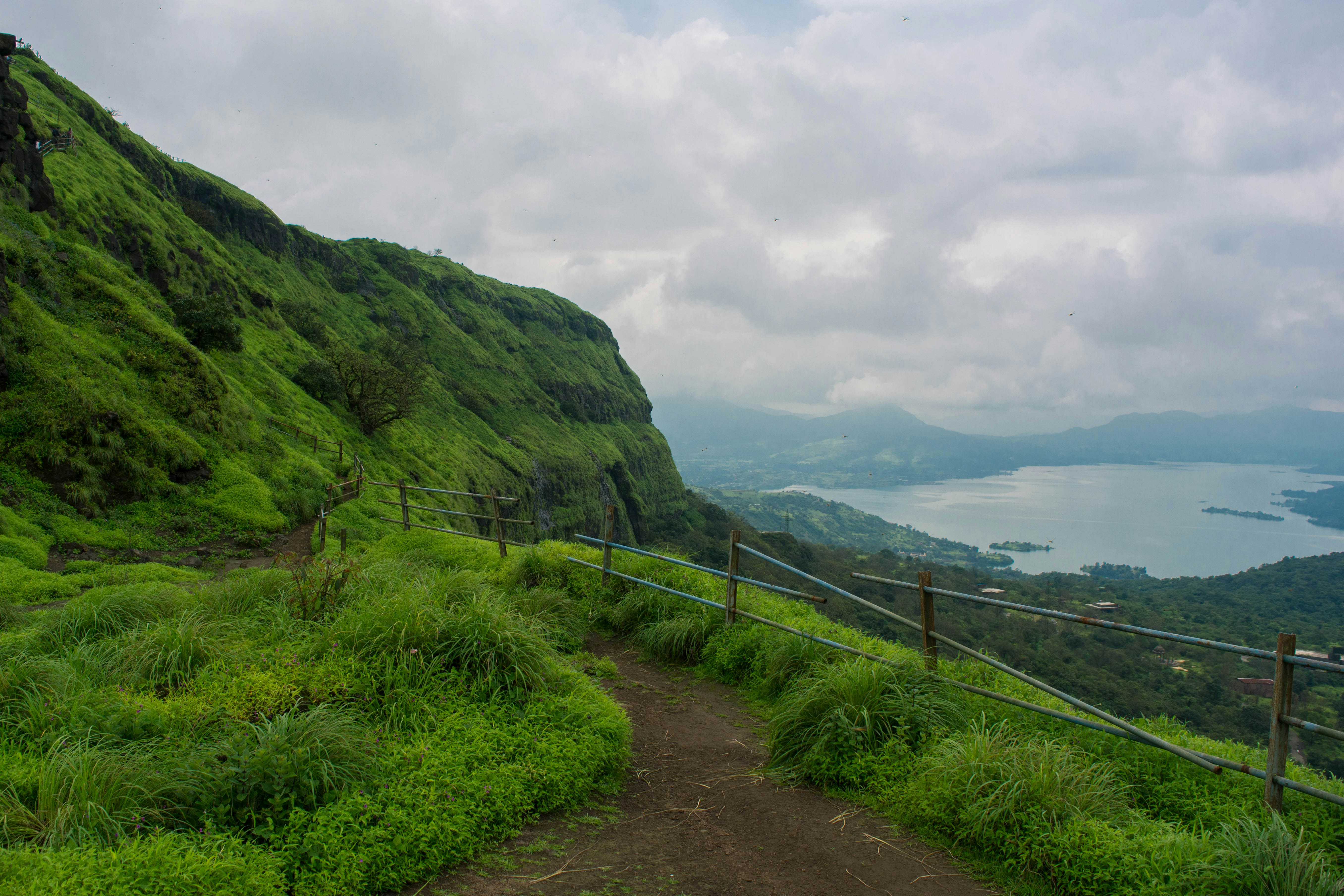 a dirt road in a valley, Lohagad is part of the Western Ghats. The hill extends to the northwest to a fortified spur, called Vinchukada (Scorpion
