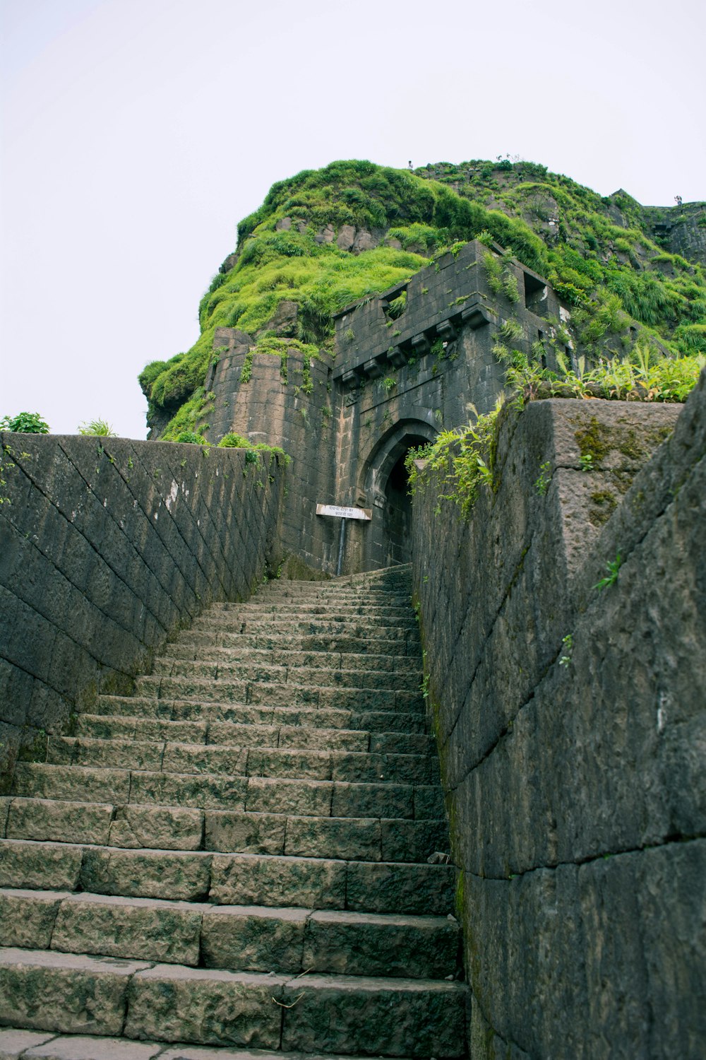 a stone staircase leading up to a hill with a stone wall