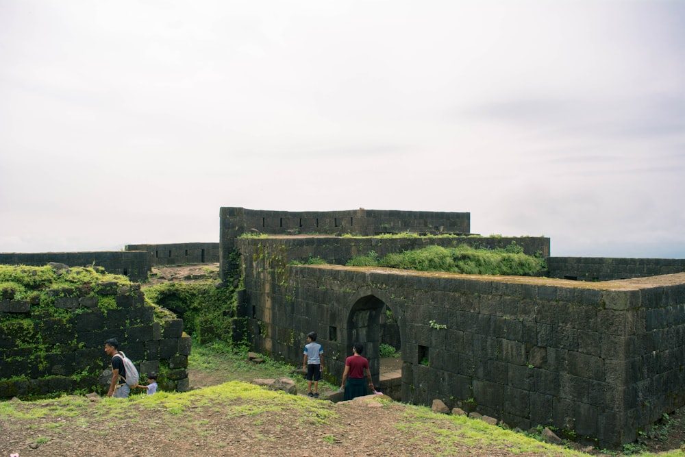 people standing in front of a stone building with a large archway