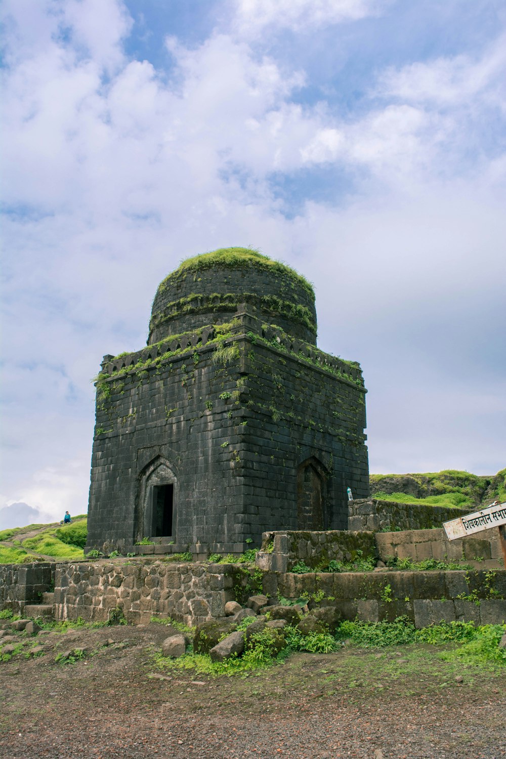 a stone building with a dome with Lohagad in the background