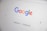 The homepage of a search engine is displayed, featuring a colorful, multi-letter logo at the top. Below the logo is a search bar with a microphone symbol and two buttons labeled 'Google Search' and 'I'm Feeling Lucky'.
