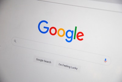 The homepage of a search engine is displayed, featuring a colorful, multi-letter logo at the top. Below the logo is a search bar with a microphone symbol and two buttons labeled 'Google Search' and 'I'm Feeling Lucky'.