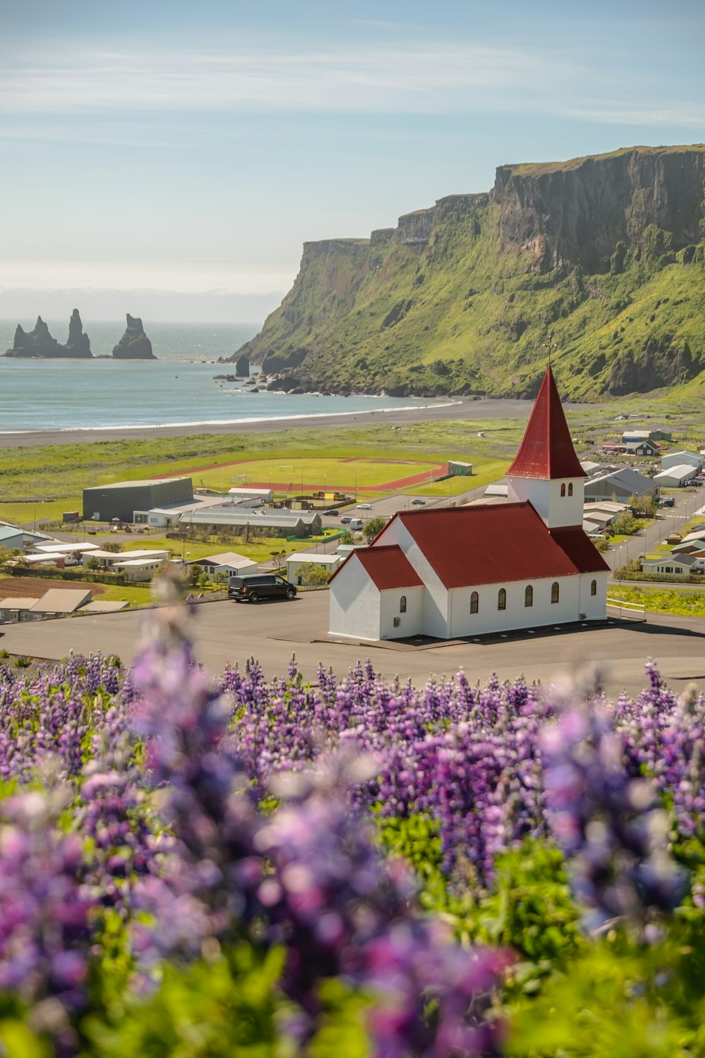 a red and white building with a red roof surrounded by purple flowers