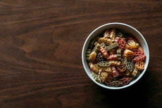 An assortment of colorful pasta shapes displayed in a rustic bowl.