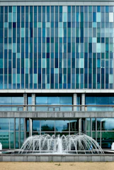 Commercial building facade being pressure washed, water droplets sparkling.