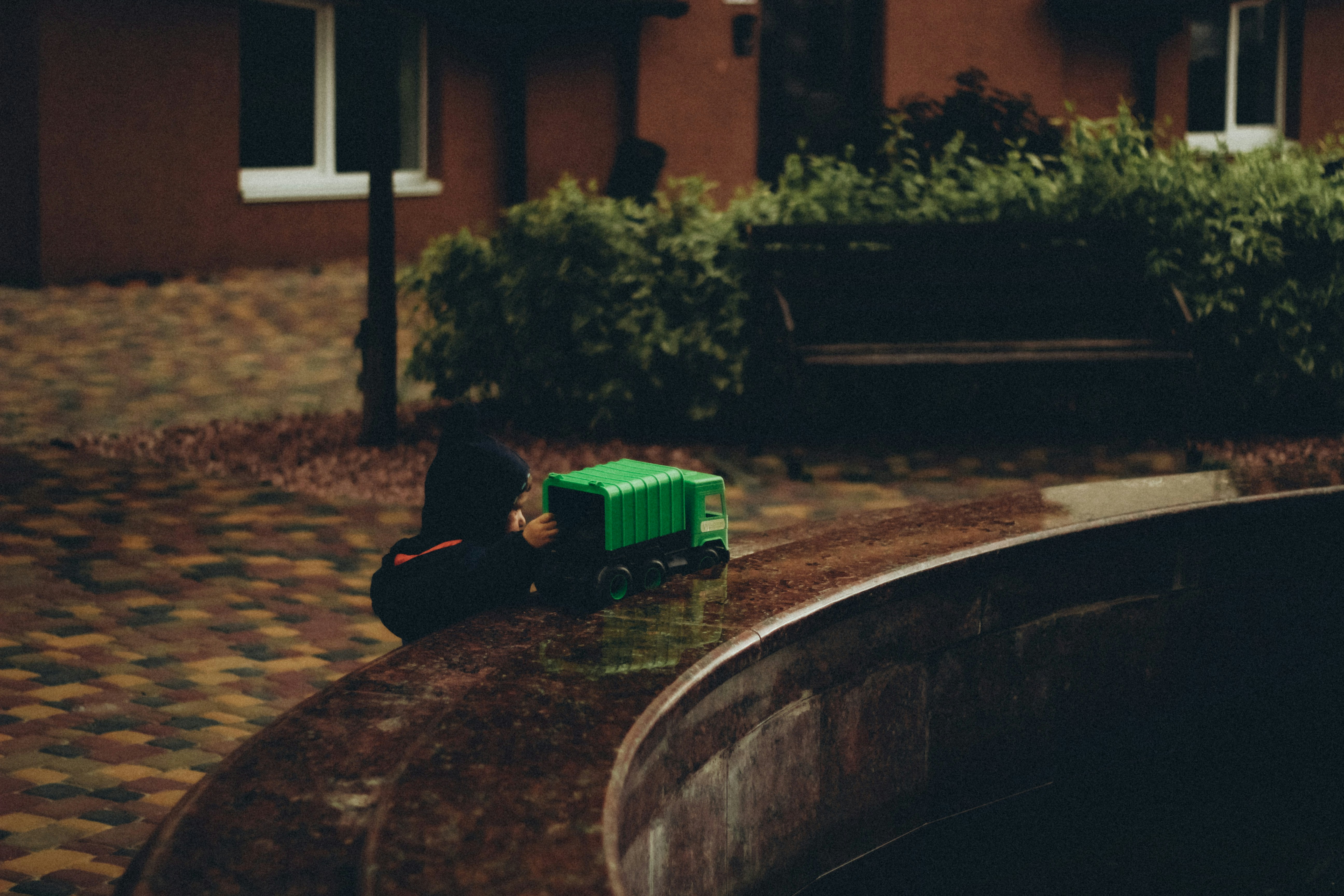 a person sitting on a bench next to a green toy truck