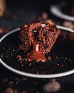 A close-up of a rich chocolate lava cake with molten center oozing onto a white plate.