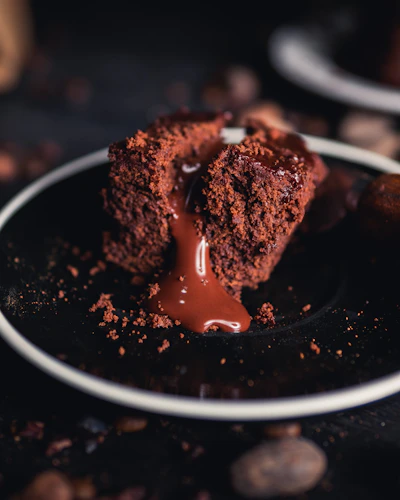 A close-up of a luscious chocolate lava cake with molten center oozing onto a white plate.