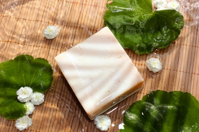 Close-up of a green herbal soap bar with fresh leaves around it