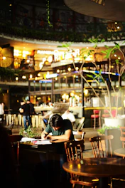 A close-up of a young author writing notes in a cozy cafe filled with books.