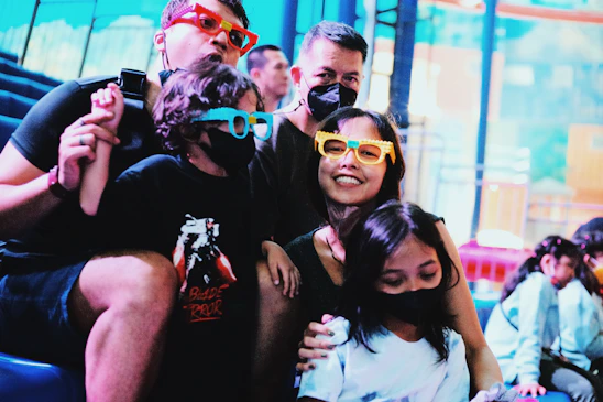 A family wearing 3D glasses enjoying an immersive 7D cinema experience with motion seats and special effects.