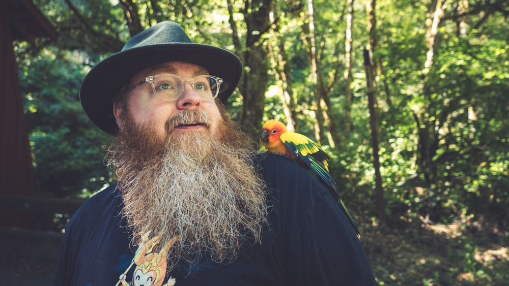 a man with a beard and a couple of birds on his shoulder
