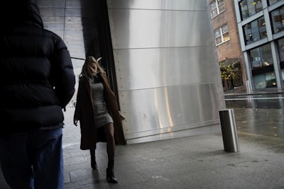 A model wearing layered street style clothes walking in an urban setting.
