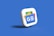 A 3D icon of a stack of cards with the Google News logo, featuring blue, green, yellow, and red colors, set against a solid blue background.