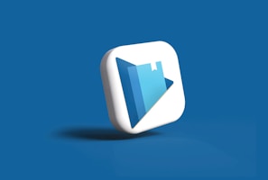 A 3D icon with a play button symbol and a book graphic is centered against a solid blue background. The icon is designed in white and shades of blue, with a modern and sleek appearance.