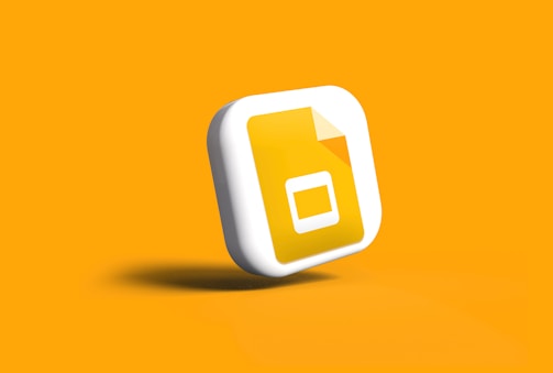 A yellow square icon with rounded edges features a white rectangle with a yellow document symbol inside. The icon appears to be rendered three-dimensionally with a soft shadow cast onto an orange background.