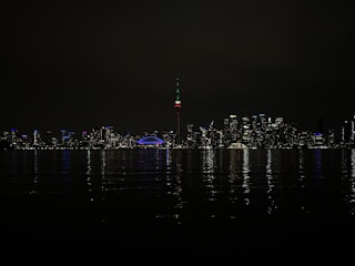 A glowing neon skyline of Toronto at night, streaked with colorful light trails.