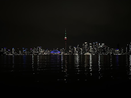 A glowing neon skyline of Toronto at night, streaked with colorful light trails.