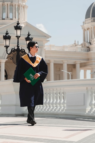 a person in a black robe and cap holding a book
