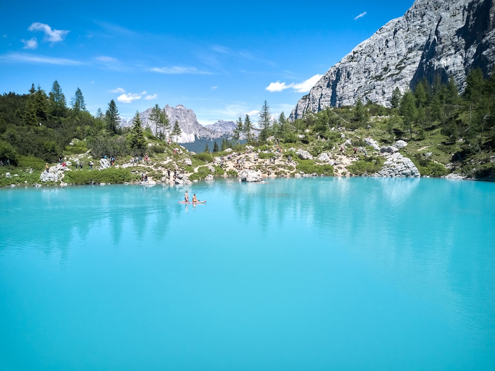 a group of people swimming in a large body of water with mountains in the background