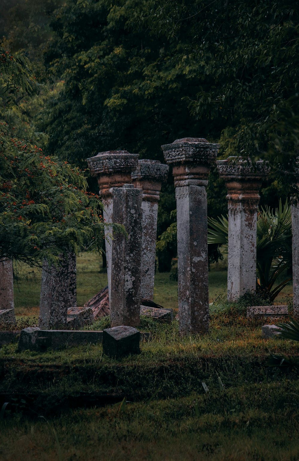 Un grupo de pilares de piedra en una zona de césped con árboles al fondo