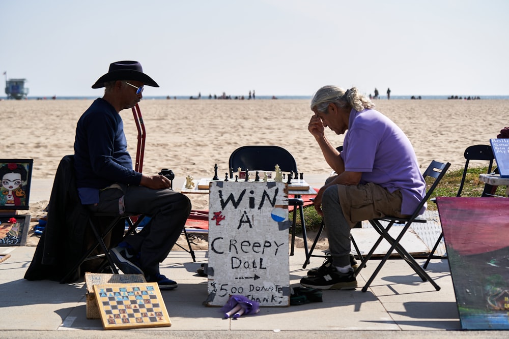 a couple of men sitting at a table with a sign on it