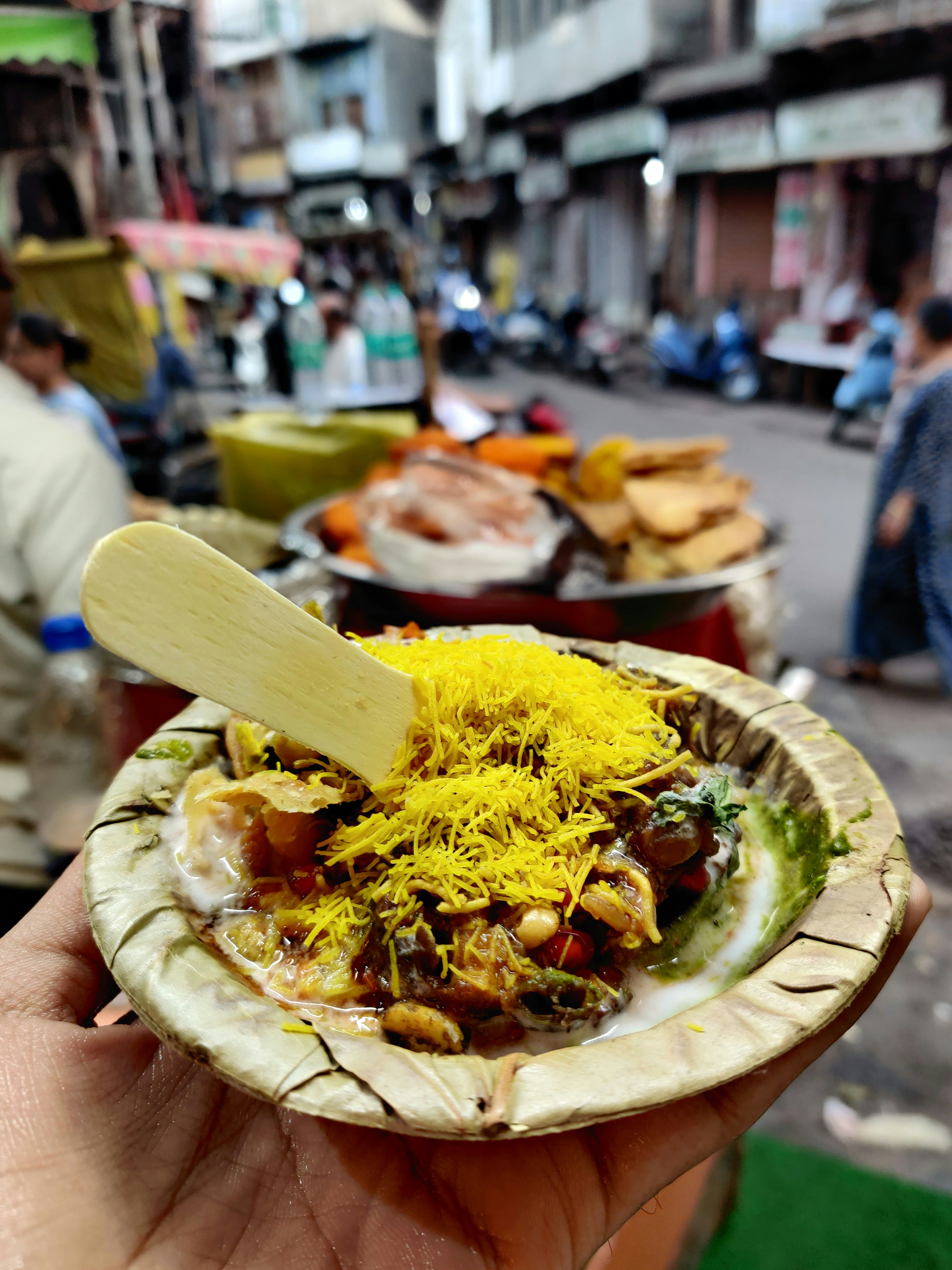 Colorful corn chaat in bowl with chutneys and sev, bright overhead lighting