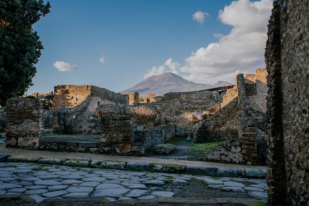 a stone walkway with a stone wall and a mountain in the background