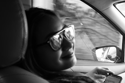 A happy driver using a digital device to get car insurance quotes on a European city street.