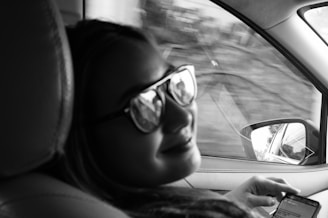 A smiling employee using the skreppa app on their smartphone while sitting in their car, with a city street visible through the window.