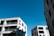 Several modern apartment buildings with multiple floors and balconies are seen against a clear blue sky.