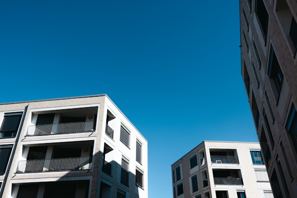 Several modern apartment buildings with multiple floors and balconies are seen against a clear blue sky.