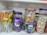 A shelf displays a variety of colorful candies in transparent plastic jars. On the left, there are lollipops with orange and yellow colors. The center jar contains Cadbury Dairy Milk chocolates, noticeable by the distinctive purple packaging. Another jar holds candies shaped like butterflies in pastel shades. On the right, wafer cones with pink and green colors are visible.
