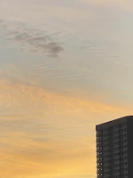 Luxurious high-rise apartment building with golden accents at sunset.