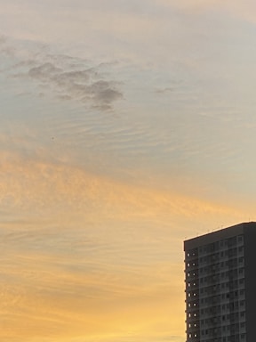 Sunset view of a high-rise building with illuminated windows.