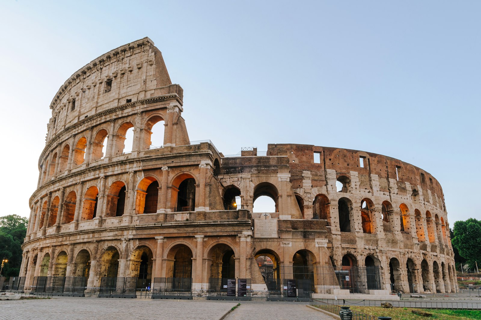 The Colosseum in Rome glowing in warm early-morning light under a clear blue sky