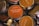 Several round, metal tins with lids featuring labels that have various aromatic scents such as Denmark Hygge and Sicily. The labels are mostly orange and beige with a mix of English and non-English languages detailing the scents.