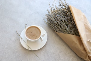 Fresh lavender sprigs next to a dark brown tea cup with a lavender interior