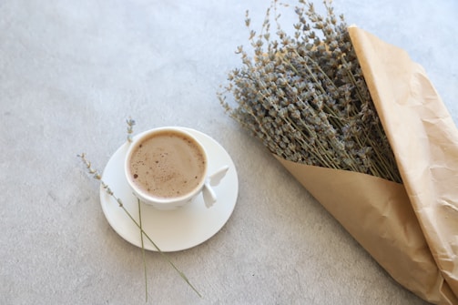Fresh lavender sprigs next to a dark brown tea cup with a lavender interior