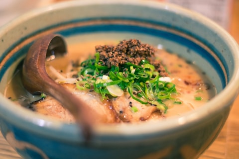a bowl of soup with meat and broccoli on a plate